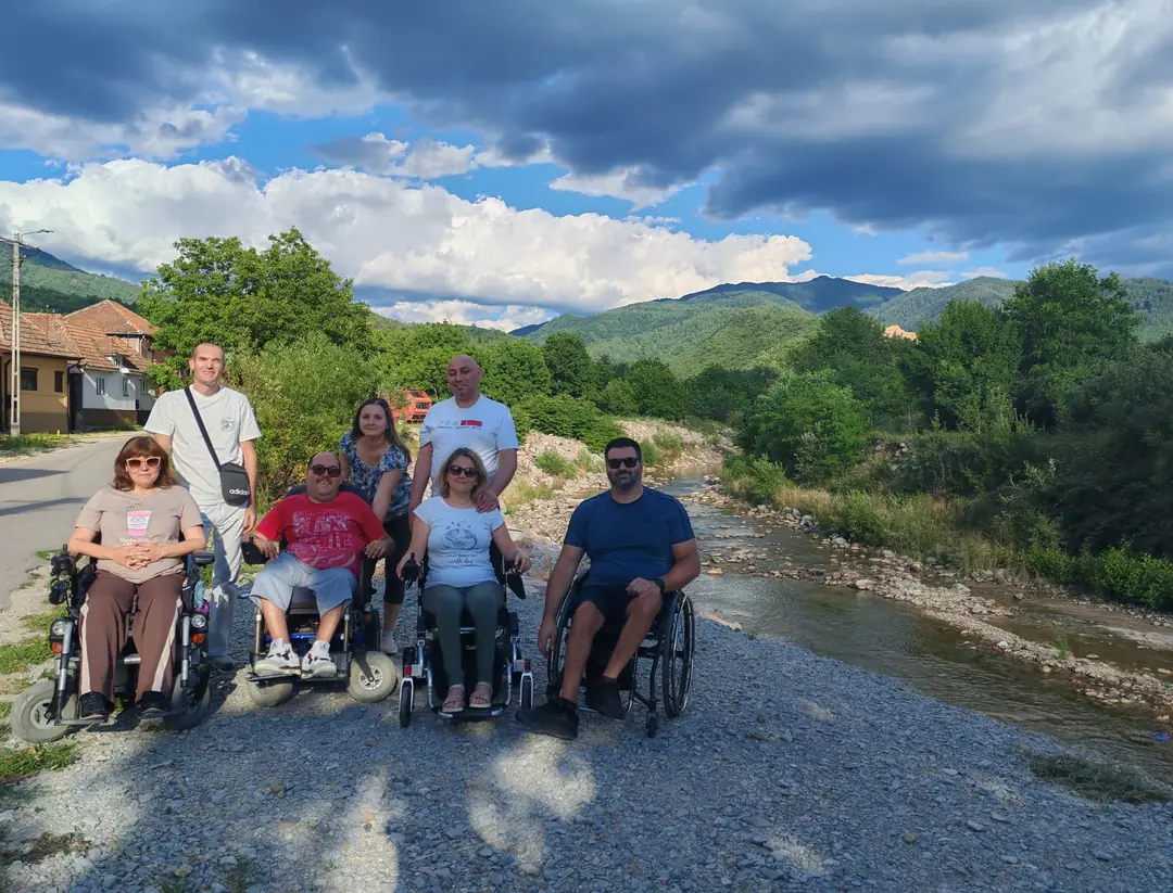 Grup pe malul unui râu, între munți
