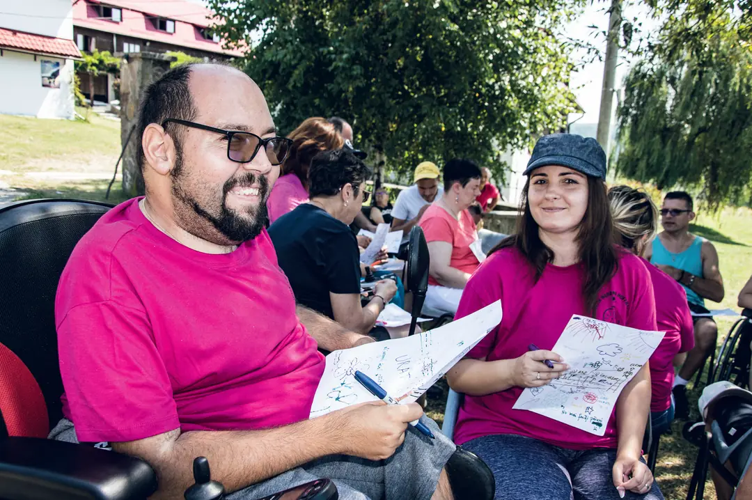 Un bărbat și o femeie în tricouri magenta, cu desene în mână