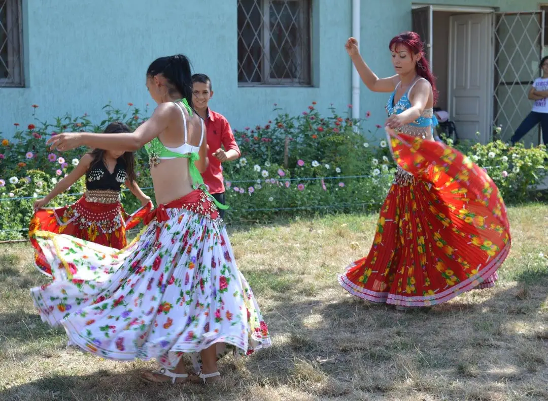 Dansatoare în fuste colorate, într-o curte însorită