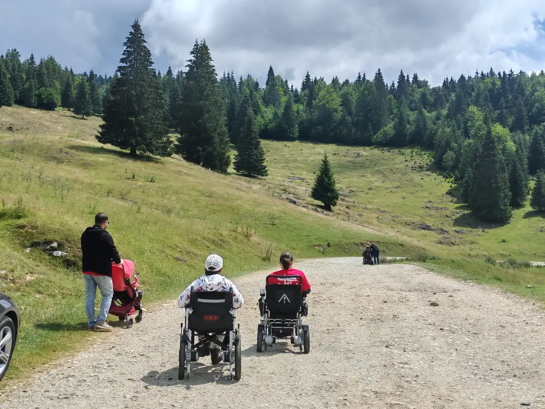 Doi oameni în scaune rulante electrice pe un drum de munte