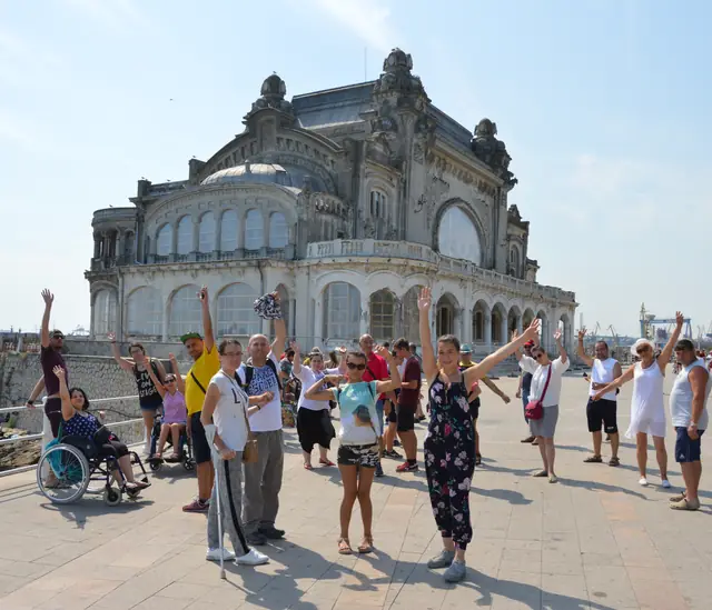 Grup cu brațele ridicate în fața Cazinoului din Constanța