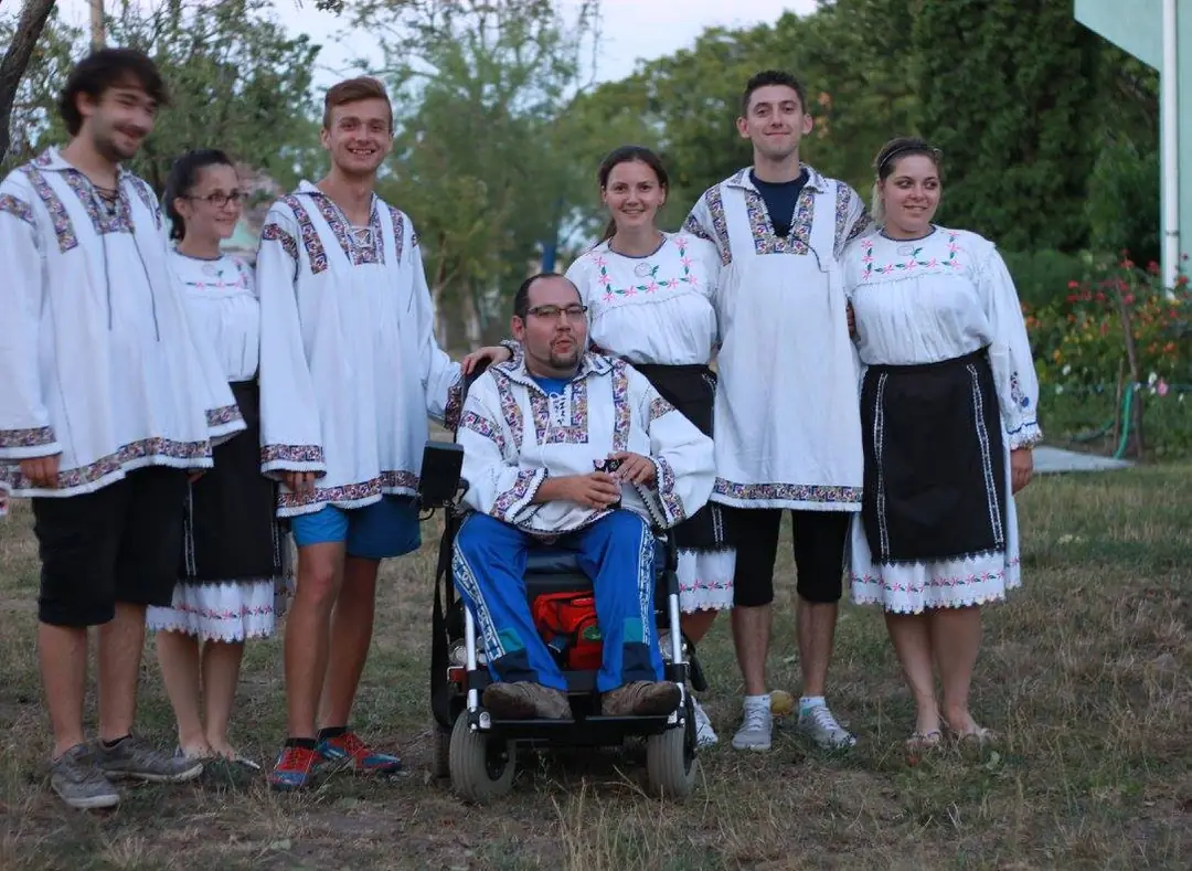 Tineri în costume populare, alături de un participant în scaun rulant